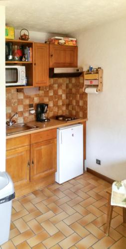 une cuisine avec des armoires en bois et un réfrigérateur blanc dans l'établissement Appartement agréable à Saint-Gervais-les-Bains de 30 m² avec piscine, à Saint-Gervais-les-Bains