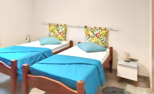 two beds in a room with blue sheets at Appartement spacieux avec vue montagne à Le Marin, 82 m². in Le Marin