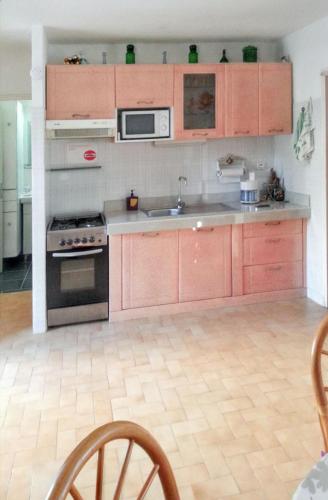 a kitchen with wooden cabinets and a stove top oven at Appartement confortable à Sainte-Luce 50 m² vue mer in Sainte-Luce