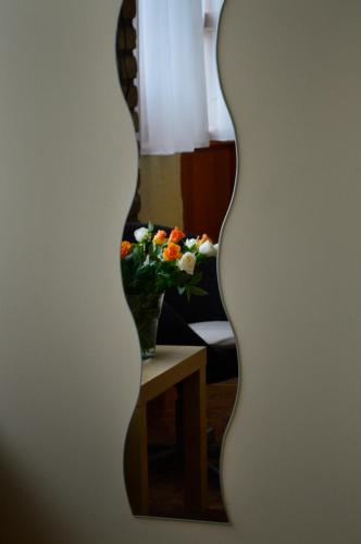 a mirror with a vase of flowers on a table at Mediterrán Vendégház in Kecskemét