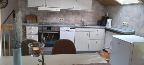 a kitchen with white cabinets and a table with chairs at Ferienwohnung am Marienbrunnen in Bayersoien