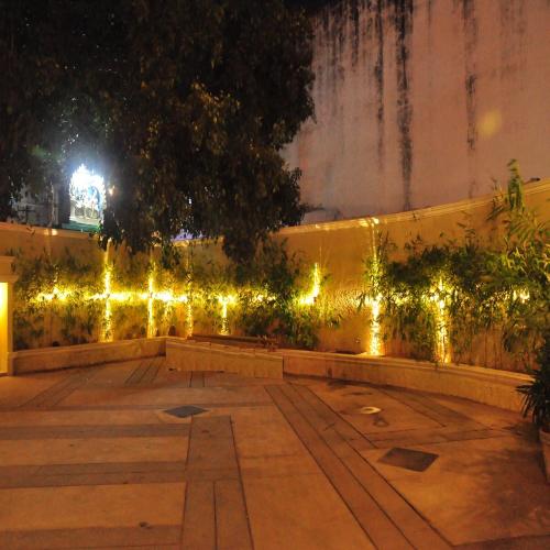 a garden with lights on a fence at night at RKN Hotel in Puducherry