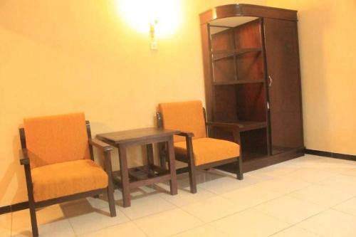 a room with two chairs and a table and a book shelf at Surya Guest House in Kanigaran