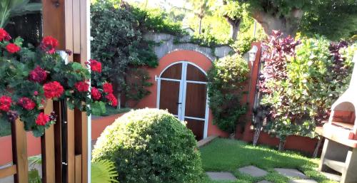 a garden with red flowers and a door at Maison charmante à Saint Paul avec vue mer et montagne in Saint-Paul
