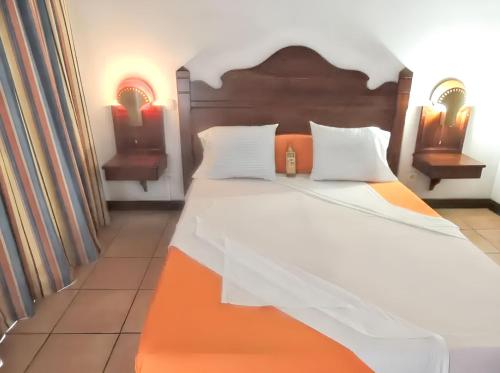 a bedroom with a large bed with a wooden headboard at Studio confortable à Sainte-Anne 40 m² jardin privé in Sainte-Anne