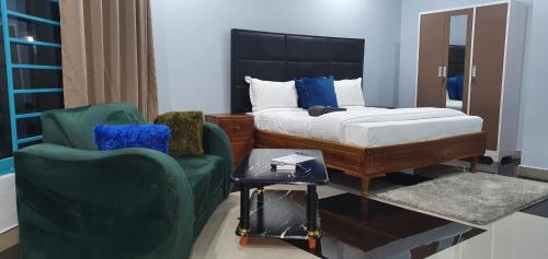 a bedroom with a bed and two green chairs at NEBCON Executive Lodge in Kitwe