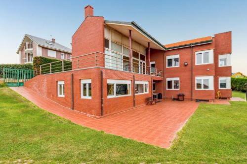 a large red brick building with a large yard at Spacious house with sea view in Liencres + jacuzzi in Liencres