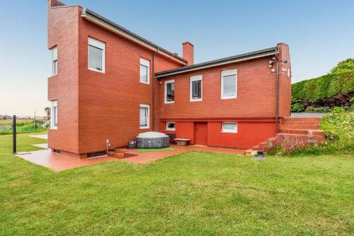 a large red brick house with a large yard at Spacious house with sea view in Liencres + jacuzzi in Liencres