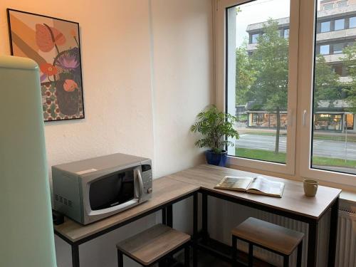 a room with a desk with a microwave and a window at City-Apartment mit Stil und Charme in bester Lage in Bielefeld