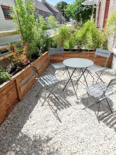 a patio with a table and chairs and some plants at Maison spacieuse à Le Vivier-sur-Mer, proches des commodités in Le Vivier-sur-Mer