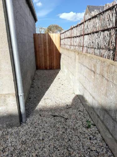 a concrete wall next to a wooden fence at Maison spacieuse à Le Vivier-sur-Mer, proches des commodités in Le Vivier-sur-Mer