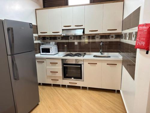 a kitchen with white cabinets and a stainless steel refrigerator at Cascadia Apartments Kigali in Kigali