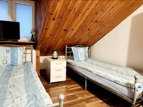 two beds in a room with a wooden ceiling at Pod Czaplą in Warsaw