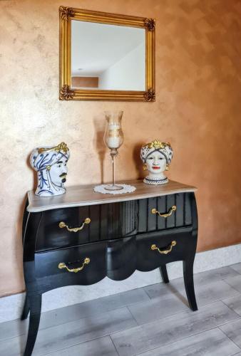 a black dresser with a mirror and two vases at Charming Villa in Fontane Bianche with Private Pool in Fontane Bianche