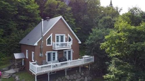 a large red house with a white porch and balcony at Yomi Chalet in Lac-Superieur