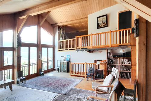 Il comprend un salon doté de plafonds en bois et d'un escalier. dans l'établissement Appartement spacieux aux Chapelles avec vue sur montagne, à Les Chapelles