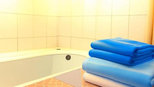 a bathroom with a tub and a stack of blue towels at Surya Guest House in Kanigaran