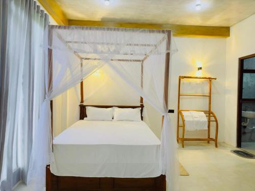 a bedroom with a canopy bed with white curtains at Sigiri Rainbow Lodge in Sigiriya
