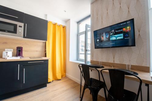 Il comprend une cuisine avec une table et des chaises ainsi qu'une télévision murale. dans l'établissement Au Nouveau Boulonnais - 4 appartements charmants pour couples, familles et groupe d'amis, vieille ville et centre ville de Boulogne sur Mer, à Boulogne-sur-Mer