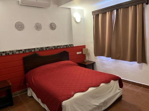 a bedroom with a red bed and a window at Easy Inn Hotel in Belize City