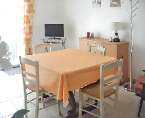 einen Esstisch mit Stühlen und einen TV in der Unterkunft Maison chaleureuse à Notre-Dame-de-Monts avec terrasse in Notre-Dame-de-Monts