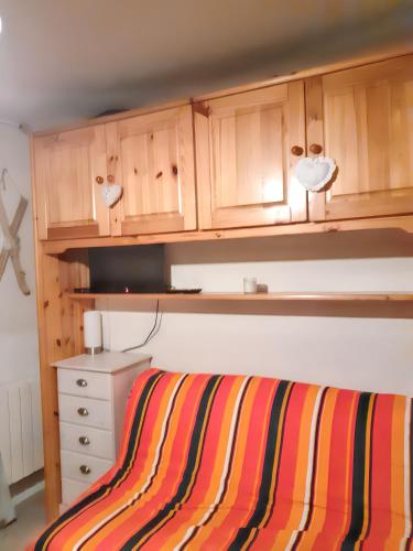 - une chambre avec des placards en bois et un lit rayé dans l'établissement Studio confortable à Allos 20 m² avec vue montagne, à Allos
