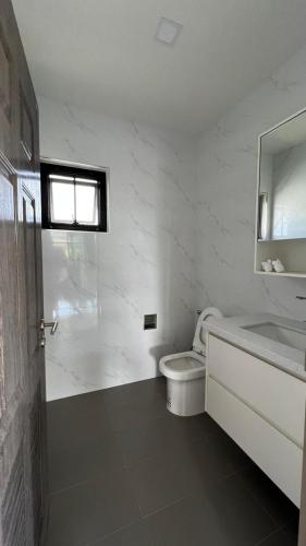 a white bathroom with a toilet and a sink at Anchan Gardens Pool Villa 23 in Hua Hin