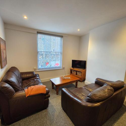 a living room with two leather couches and a table at The Borough Apartment in Kent