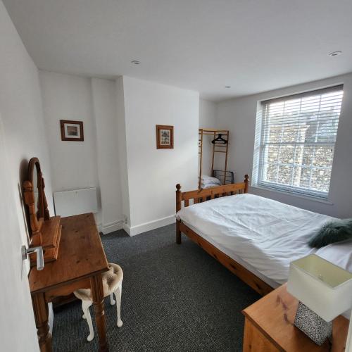 a bedroom with a bed and a desk and a window at The Borough Apartment in Kent