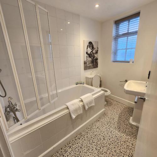 a bathroom with a tub and a toilet and a sink at The Borough Apartment in Kent