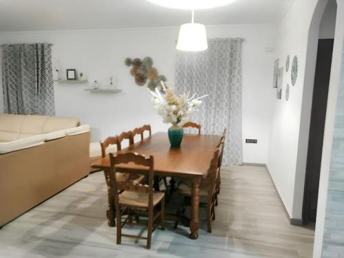 a dining room table with chairs and a vase of flowers at Charming chalet in Prado del Rey with private pool in Prado del Rey