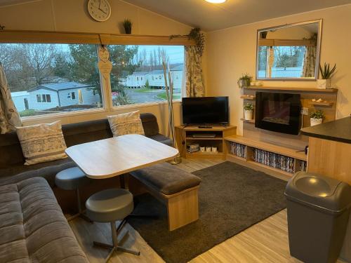 a living room with a couch and a table and a tv at Rockley Park Private Holiday Homes in Poole