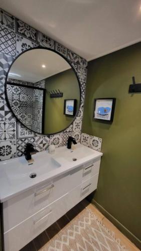 une salle de bain avec un lavabo et un miroir dans l'établissement Logement proche de la mer, à Bernières-sur-Mer