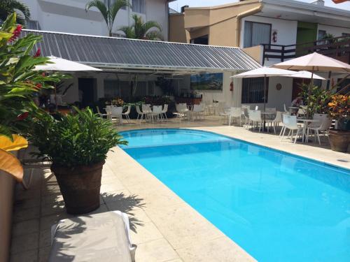 a swimming pool with chairs and tables and umbrellas at Hotel Residence Inn Suites Cristina in San José