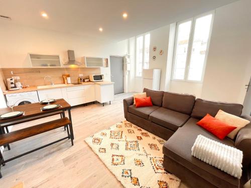 a living room with a couch and a kitchen at L'Ibéris - Toutes les commodités dans la rue - 1er étage in Auch