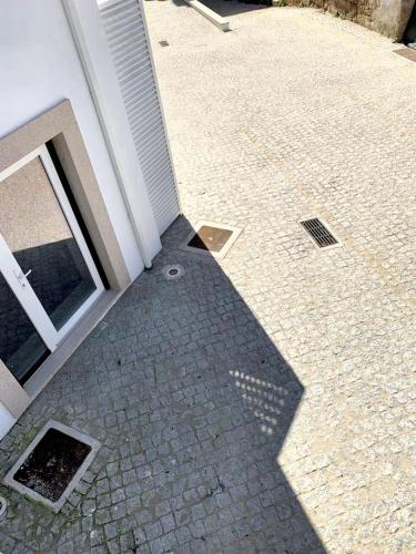 a shadow of a building on a brick sidewalk at Cozy house in Castelo Branco, 60 m², city view balcony in Castelo Branco