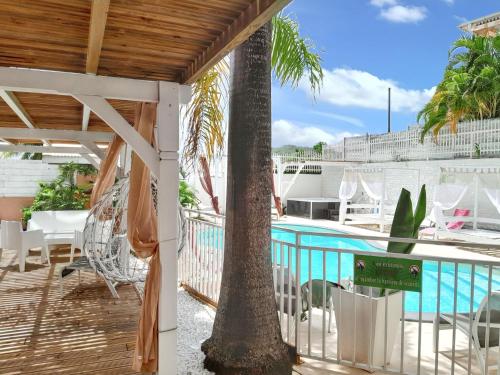 a patio with a pool and a palm tree at Studio charmant à Sainte-Anne avec piscine partagée - 30 m² in Sainte-Anne