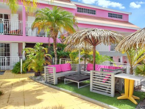 a pink building with pink benches and palm trees at Studio charmant à Sainte-Anne avec piscine partagée - 30 m² in Sainte-Anne