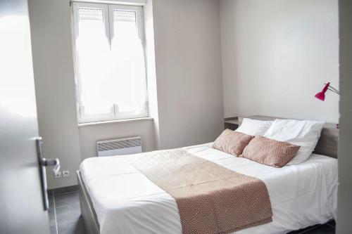 une chambre avec un lit avec des draps blancs et une fenêtre dans l'établissement Appartement spacieux à Carcassonne 48 m² avec parking, à Carcassonne