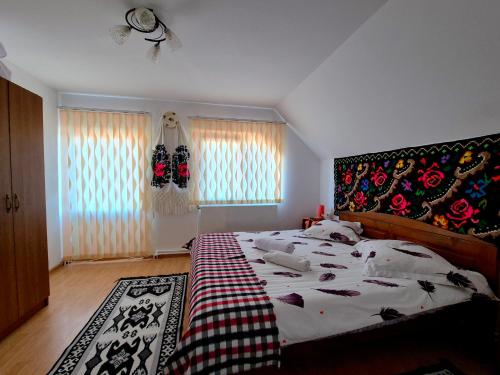 a bedroom with a large bed with a patterned headboard at Pensiunea Inima Maramureșului in Breb