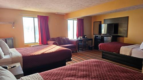a hotel room with two beds and a flat screen tv at Budgetel inn & Suites in Fort Scott