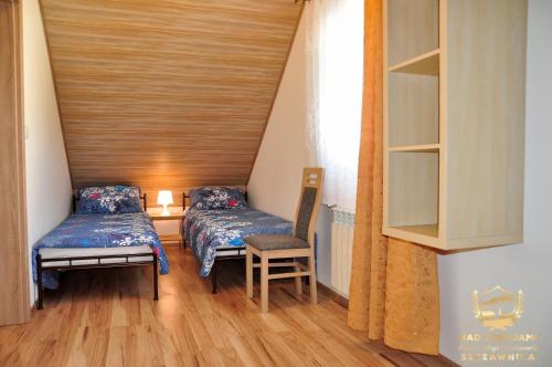 a room with two beds and a chair in it at "Nad Zdrojami" Domek Kowalczyk in Szczawnica