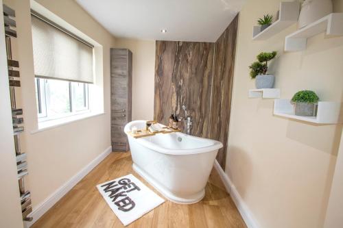 a bathroom with a white bath tub and a window at Gym I Cinema I Hot tub I Games room at Copper Beech in Shrewsbury