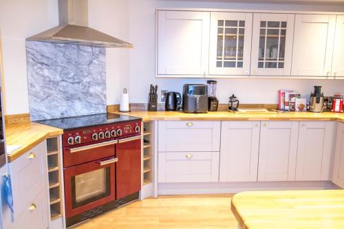 a kitchen with white cabinets and a red stove at Gym I Cinema I Hot tub I Games room at Copper Beech in Shrewsbury