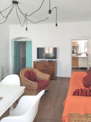 - un salon avec deux chaises et une télévision à écran plat dans l'établissement Appartement charmant à Algajola avec terrasse, à Algajola