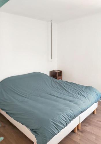 a bed in a white room with a blue blanket at Appartement charmant à Algajola avec terrasse in Algajola