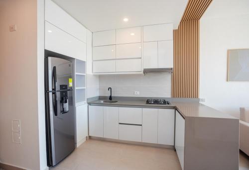 a kitchen with white cabinets and a stainless steel refrigerator at Exclusive condo with spectacular SEA VIEW! in Santa Marta
