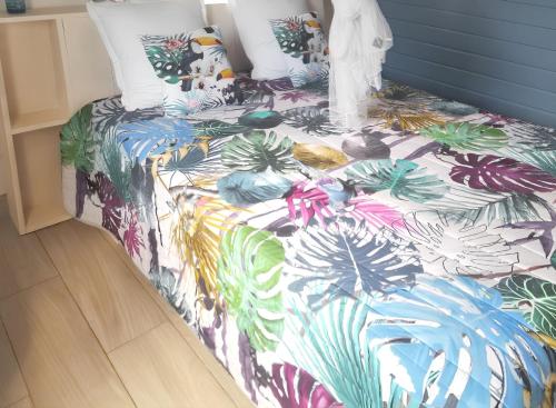 un letto con un piumone colorato con delle piante sopra di Bungalow charmant Le Moule + Jardin a Le Moule