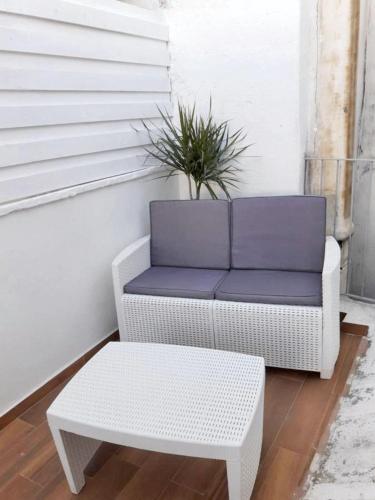 a white wicker chair and a coffee table with a plant at Charming apartment in Polignano a Mare with terrace. in Polignano a Mare