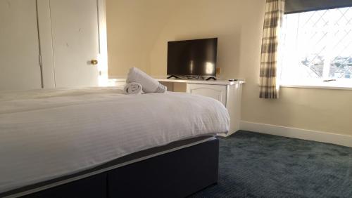 a bedroom with a bed and a tv and a window at Ye Olde Hotel in Leuchars